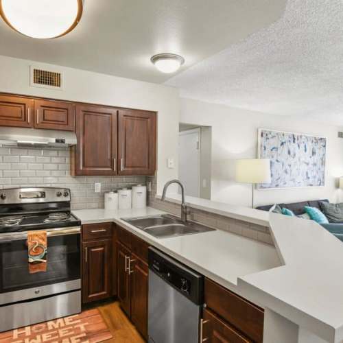 View of living room from kitchen island with stainless steel sink with waterfall faucet at Walker Landing in Aurora, Colorado, 