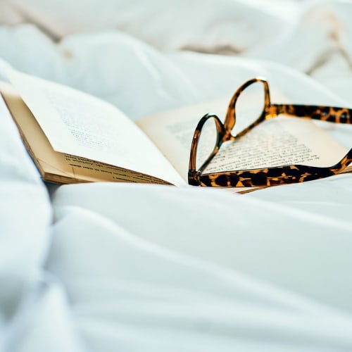 Glasses and a book resting on the bed at Harvest at Fiddyment Ranch in Roseville, California