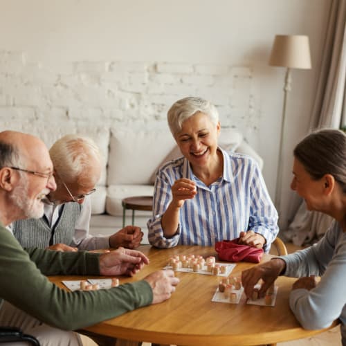 Group of residents playing dominoes together at Oxford Vista Wichita in Wichita, Kansas