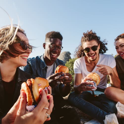 Happy friends eating burger near Terra Vida in Carmichael, California