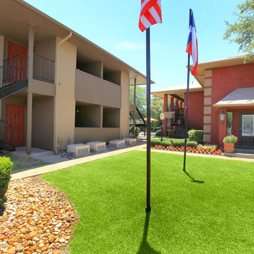 Two flag poles in front of an apartment building at The Granite at Tuscany Hills in San Antonio, Texas