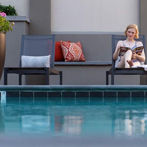 Resident relaxing in a lounge chair by the pool at 1801L Apartments in Sacramento, California