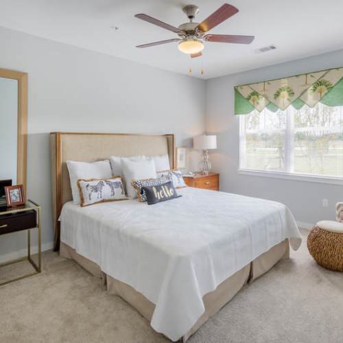 A furnished bedroom with a ceiling fan in a model apartment at Reserve at River Place in Youngsville, Louisiana