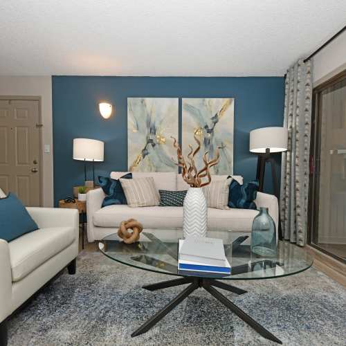 A model unit with white couches and blue accents in a living room at Ascent Apartment Homes in Asheville, North Carolina