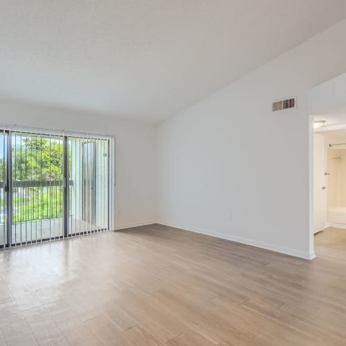 Living room with wood-style flooring and door out to a private balcony at Cascades at the Hammocks in Miami, Florida