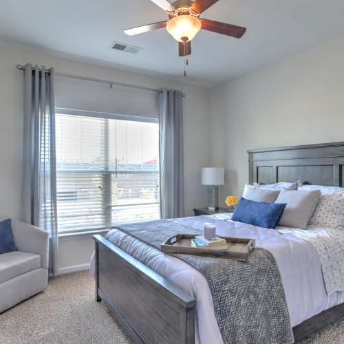 Bedroom with a comfortable bed, ceiling fan and large windows at 10 Newbridge in Asheville, North Carolina