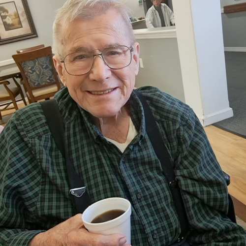 Resident with fun hat smiling while getting ready to enjoy meal at Saunders House in Wahoo, Nebraska