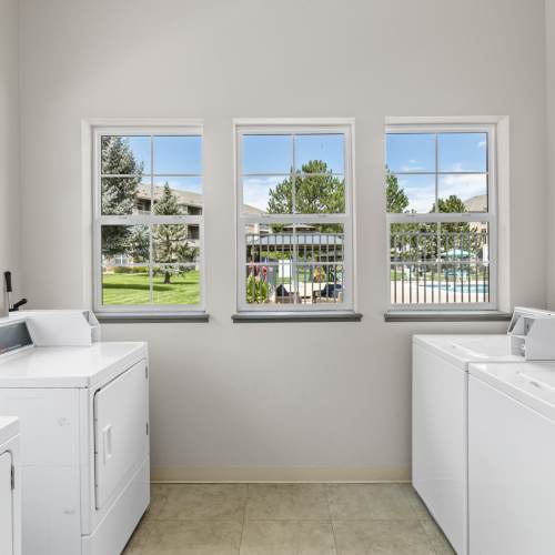 A well-lit laundry room with several washers and dryers at Fox Ridge in Longmont, Colorado