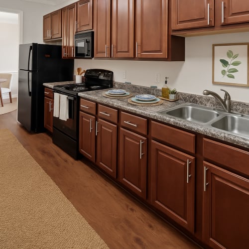 Fully equipped kitchen with granite countertops stainless steel appliances like a refrigerator, stove, and drawer microwave at Avalon At Sweeten Creek in Arden, North Carolina