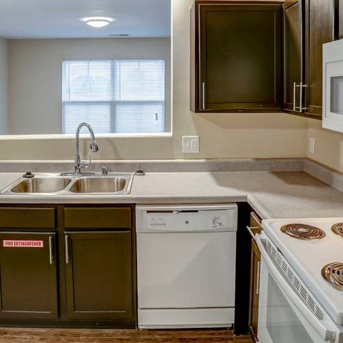 Modern kitchen with granite countertops, stainless steel appliances, and wood-style flooring at Tristan Ridge in Eminence, Kentucky