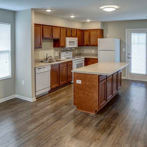 Open layout kitchen with granite countertops, stainless steel appliances, and wood-style flooring at Brea's Crossing Senior Living II in Shelbyville, Kentucky