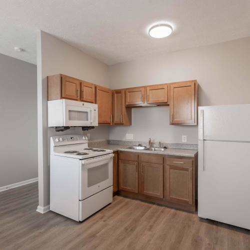 Bright kitchen with wooden cabinets and white appliances at St. Clairsville Courtyard in St. Clairsville, Ohio