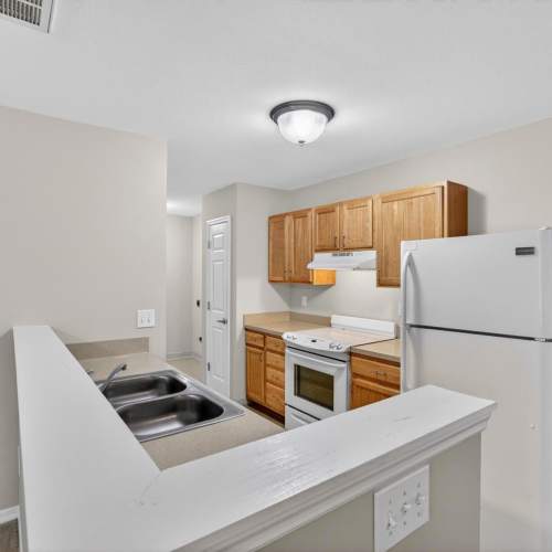 Kitchen with wooden cabinets, white appliances, and open layout at Crowfield Greene in Goose Creek, South Carolina