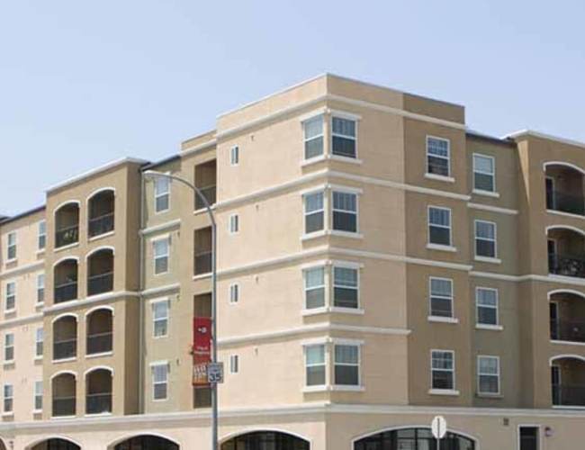 Community building with car parking at Maywood Villas in Maywood, California