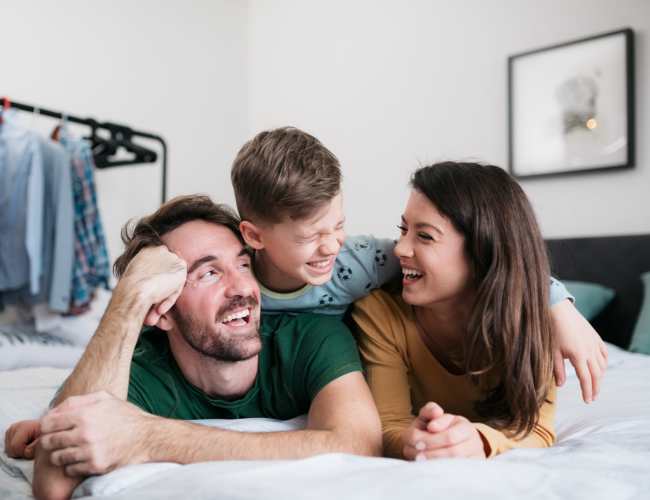 Family playing together on bed at Green Oaks Apartments in Houston, Texas