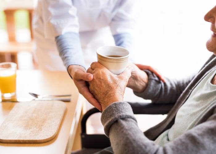 Staff assisting resident with a cup of coffee in the dining room at Westminster Memory Care in Aiken, South Carolina