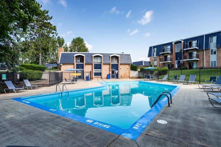 Sparkling pool surrounded by lounge chairs and lush greenery at The Grove in Battle Creek, Michigan