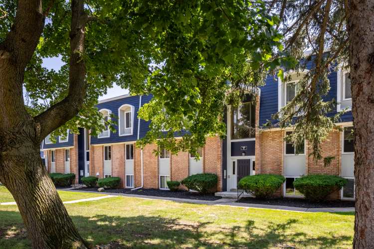 Charming brick facade with lush greenery and inviting entrance at The Grove in Battle Creek, Michigan