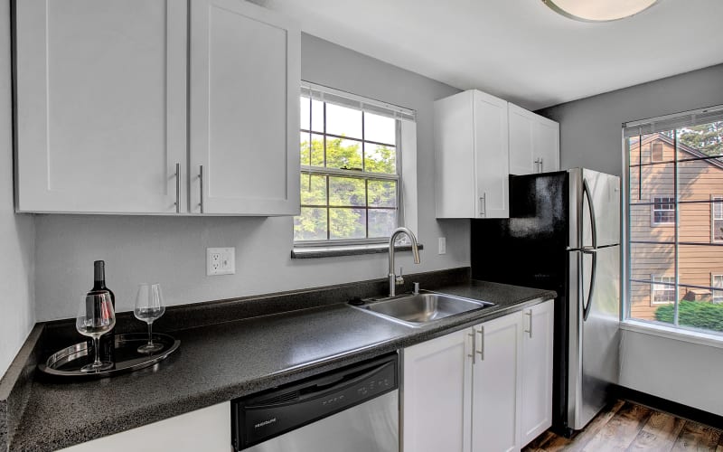 Renovated kitchen with white cabinets and stainless steel appliances at Waters Edge Apartments in Kent, Washington