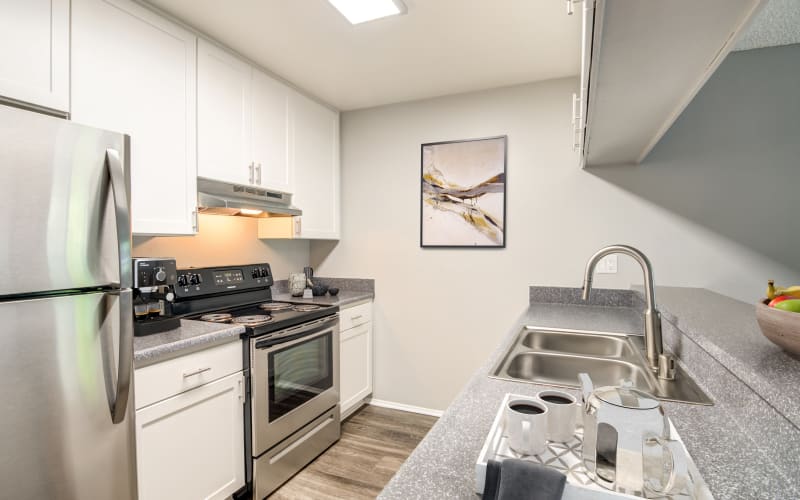 Renovated kitchen with white cabinets and stainless steel appliances at Hillside Terrace Apartments in Lemon Grove, California