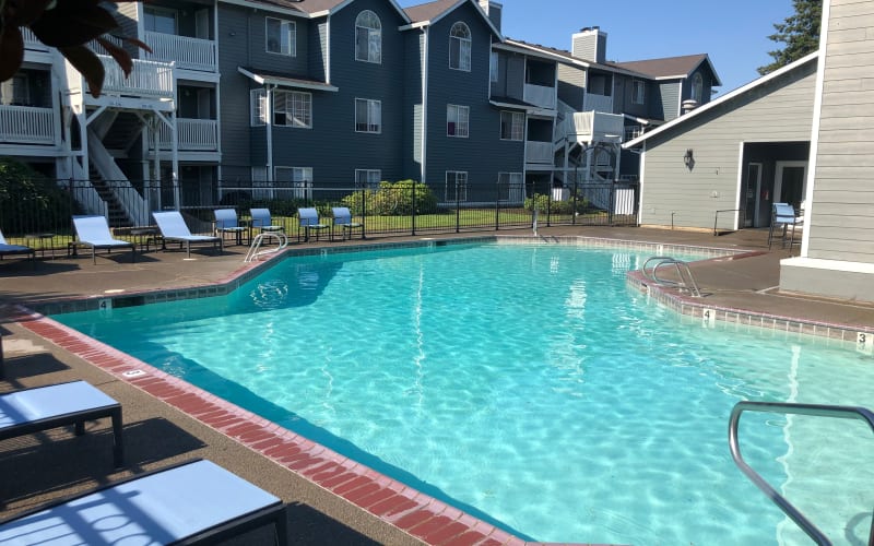 The sparkling resort-style swimming pool with new lounge chairs at Walnut Grove Landing Apartments in Vancouver, Washington