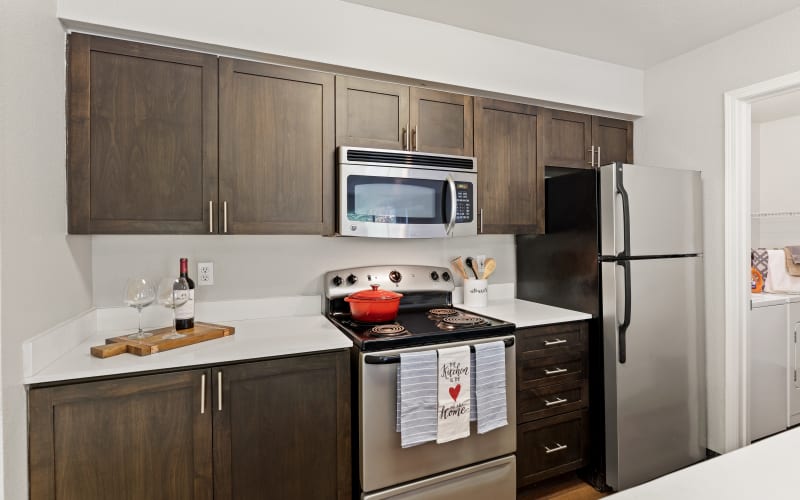 A renovated kitchen with brown cabinets, a bar area and stainless steel appliances at HighGrove Apartments in Everett, Washington