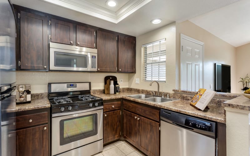 Espresso cabinets, stainless steel appliances, and ceramic tile floors in the kitchen at Village Oaks in Chino Hills, California