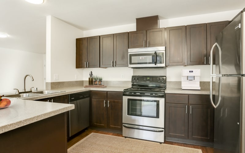 Renovated kitchen with brown cabinetry and stainless steel appliances at The Addison Apartments in Vancouver, Washington
