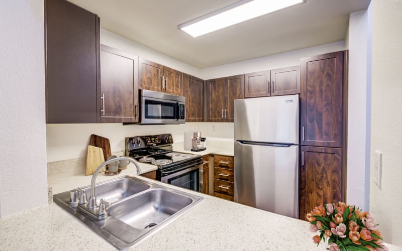 Renovated kitchen with brown cabinets at Tuscany Village Apartments in Ontario, California