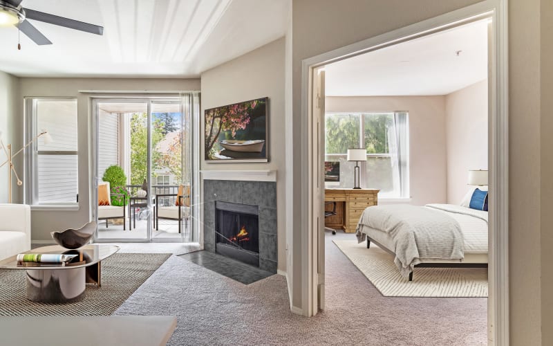 Spacious master bedroom and living room with fire place with plush carpeting at HighGrove Apartments in Everett, Washington