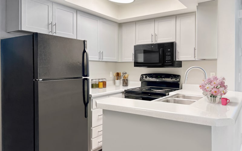 Kitchen with white cabinets and black appliances in an apartment at Royal Farms Apartments in Salt Lake City, Utah