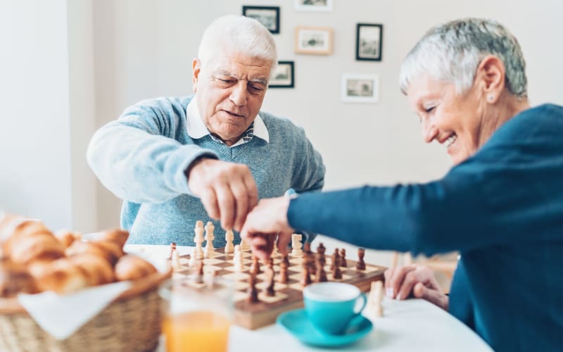 Senior couple enjoying a game of chess together during their Respite stay at our senior living community here at Grand Villa of Boynton Beach in Florida