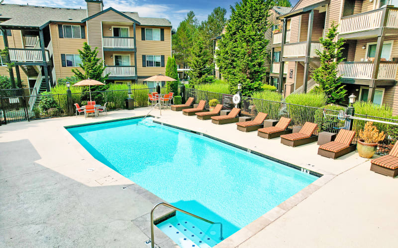 Sparking pool view with lounge chairs at Newport Crossing Apartments in Newcastle, Washington