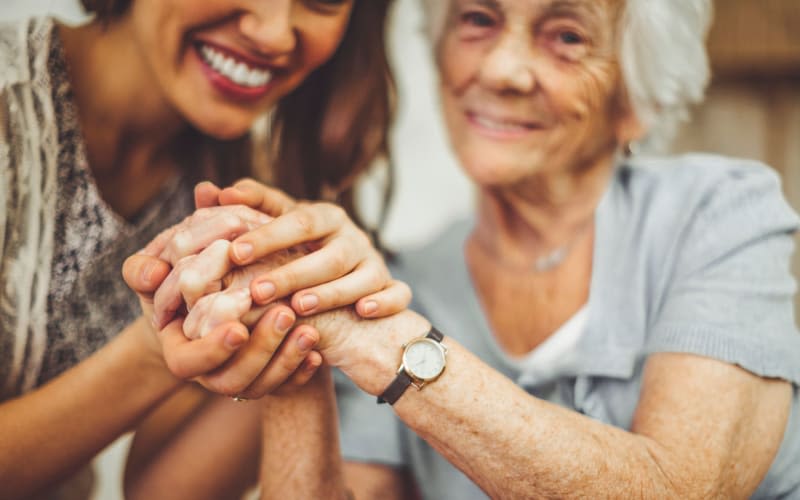 Resident holding hands with caregiver at The Pineapple House at Sapphire Lakes in Naples, Florida