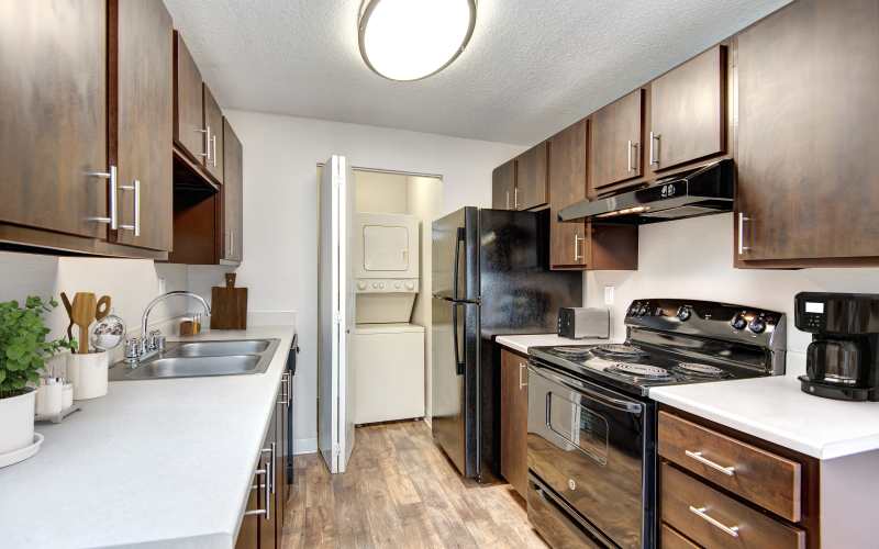An updated kitchen with brown wood cabinets at Wellington Apartments in Silverdale, Washington