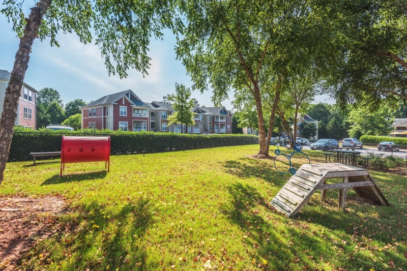 Onsite dog park with agility course partially shaded by mature trees at 200 East in Durham, North Carolina