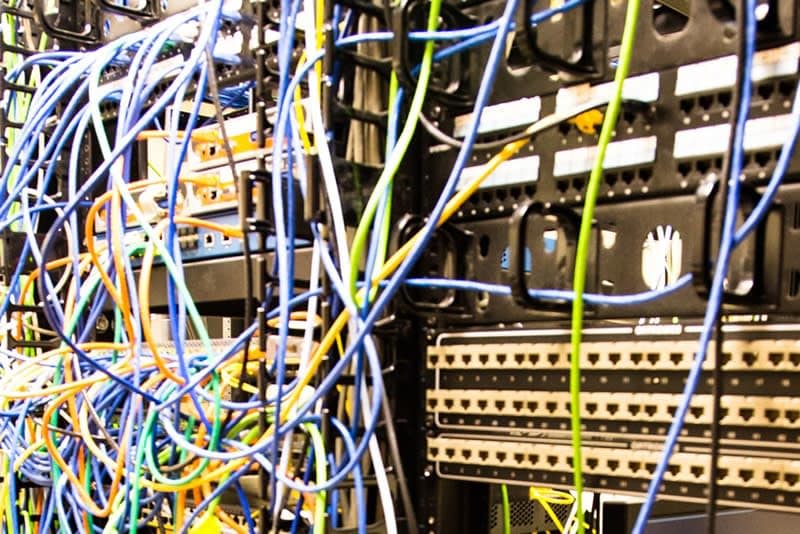 Computer network rack with multi-colored network cables connecting various rack-mounted devices.