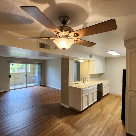 Living room with a ceiling fan and carpet at Cobble Creek Apartment Homes in Chico, California