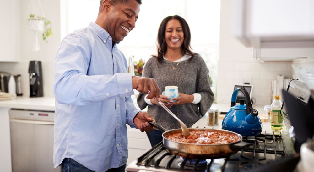 A couple cooking a delicious meal in their modern kitchen at Avemore Apartment Homes in Charlottesville, Virginia