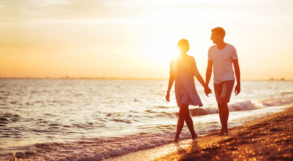 Couple holding hands while walking on beach near Beachside Apartments in Satellite Beach, Florida