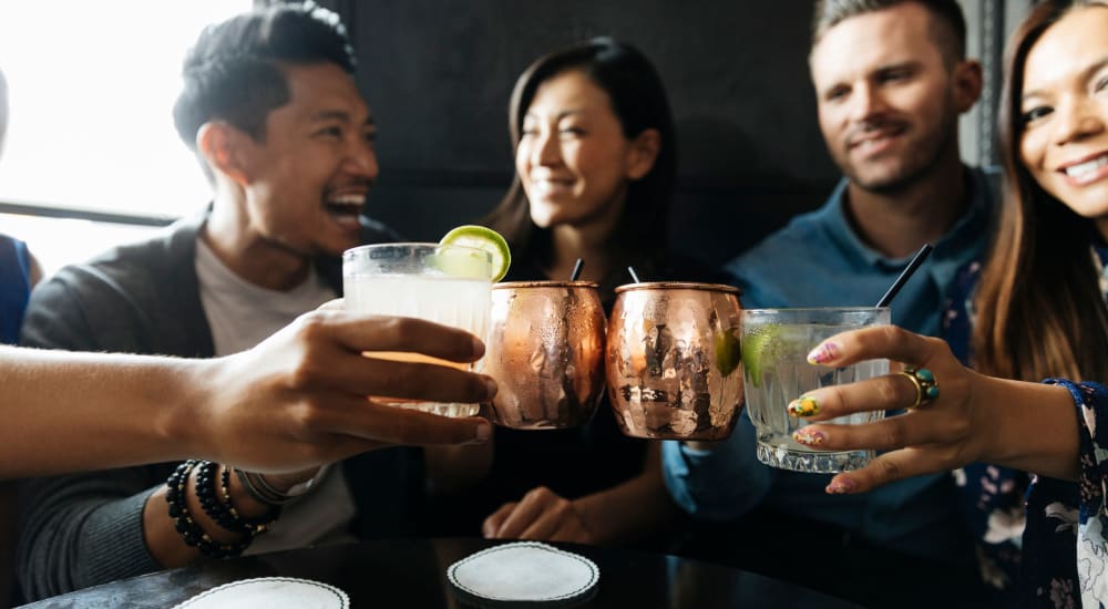 Friends laughing and enjoying drinks at a restaurant at Bellrock Upper North in Haltom City, Texas