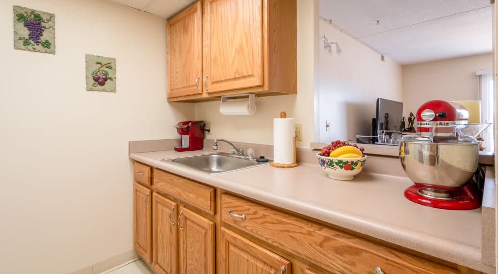 Fully equipped kitchen with natural wood cabinetry at Village Square Apartments in Williamsville, New York
