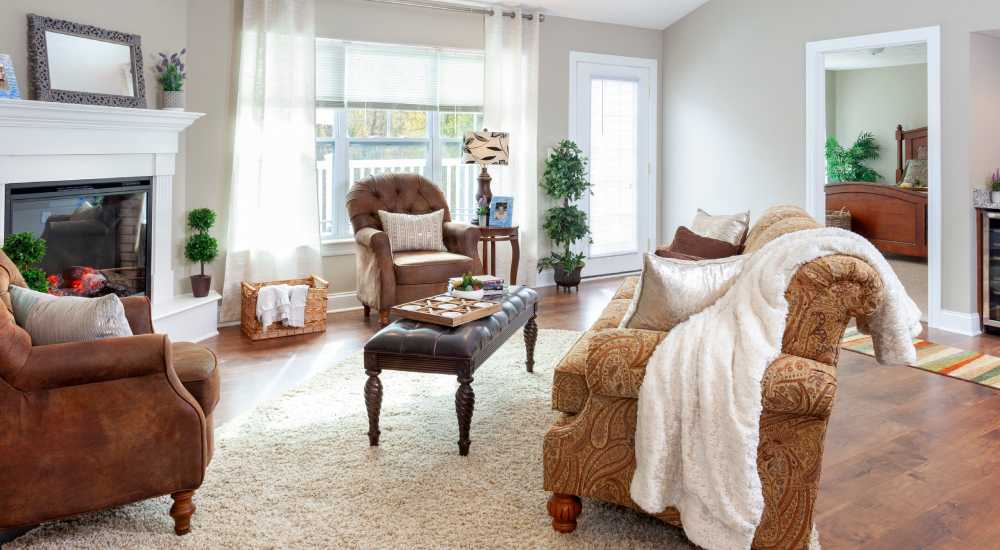 A cozy living room with a fireplace and leather couches in a model home's living space at Fairways Villas II Apartments in Victor, New York