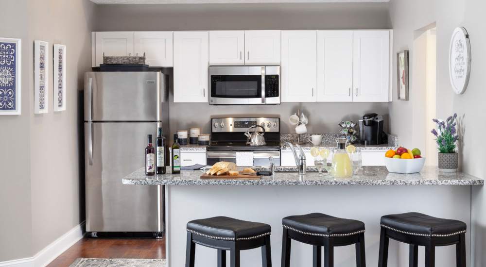 A modern kitchen with stainless-steel appliances and granite countertops at Fairways Villas II Apartments in Victor, New York