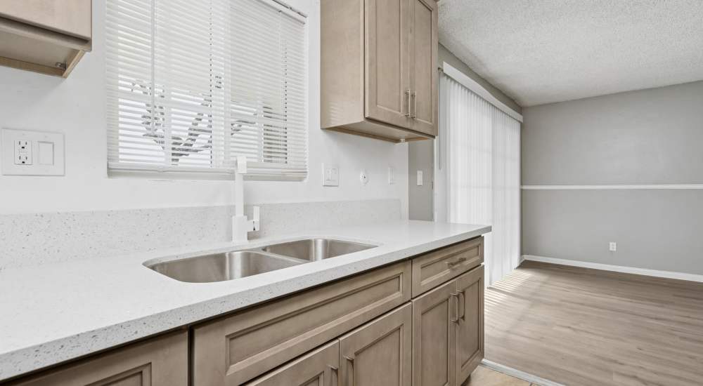Modern kitchen with window and wood cabinet at Newland Garden Apartments in Garden Grove, California