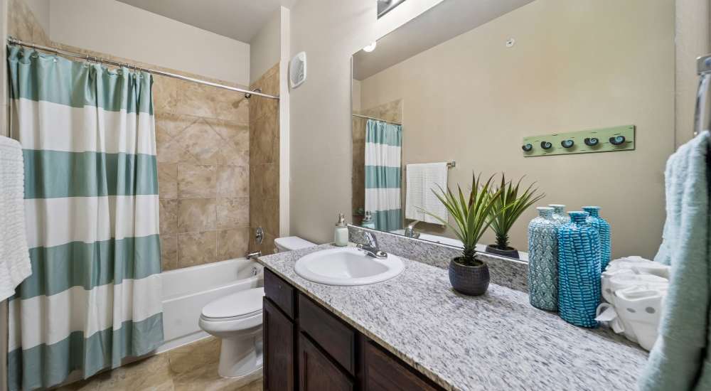 Bright bathroom with vanity, commodore, and tub and shower combo at Vistas at Red Creek in San Angelo, Texas