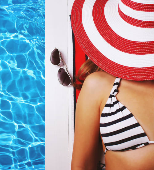 Woman in the striped bikini sporting a red and white striped hat floating in pool at Heritage Plaza in San Antonio, Texas