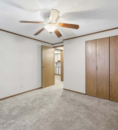 Bedroom with carpet, ceiling fan, closet, and wood doors at Live Louisville Apartments in Louisville, Kentucky
