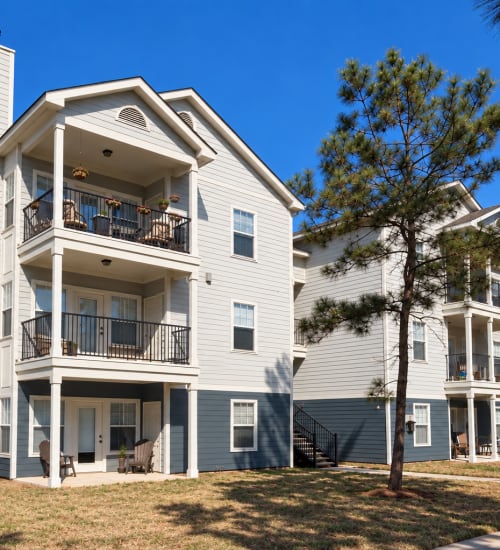 Modern apartment building with balconies, garages, and courtyard tree at Botanica in Mandeville, Louisiana
