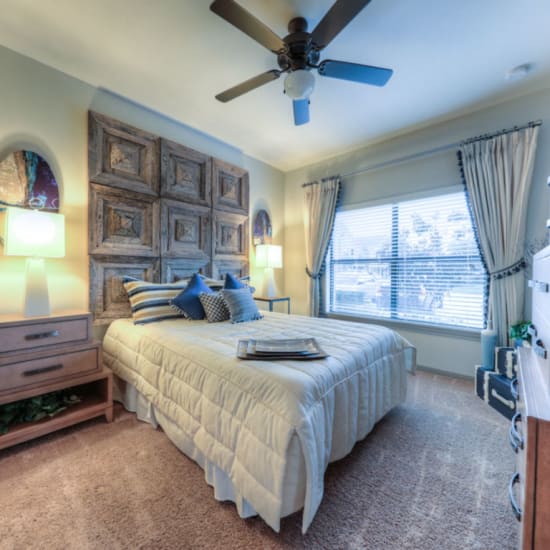 Bed and nightstand in a model home's bedroom at Avenues at Shadow Creek Ranch in Pearland, Texas